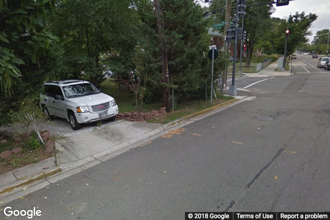 A Street View image of a road with a short stretch that is missing a sidewalk