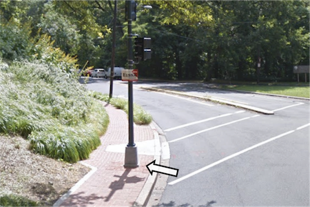 A Street View image of a street light pole in the middle of the sidewalk